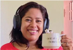 A woman wearing headphones holding a coffee mug
