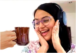 A woman wearing headphones seeing a cup of coffee