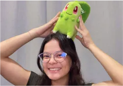 A woman holding a green stuffed animal on top of her head